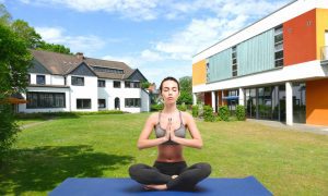 Sport- und Bildungszentrum Malente - Frau in Yogahaltung vor dem Haus