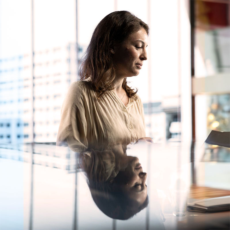 Frau in ruhiger Arbeitsatmosphäre bei reflektierender Tätigkeit an einem Tisch