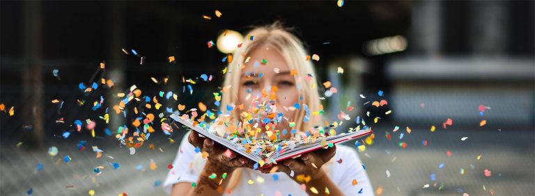 Seminarhauspartner.Blog | Vorteilswelt | Junge Frau bläst Konfetti aus einem Buch