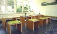 Sport- und Bildungszentrum Malente - Aufenthaltsraum Premiumzimmer - Tische und Bänke mit grünen Kissen